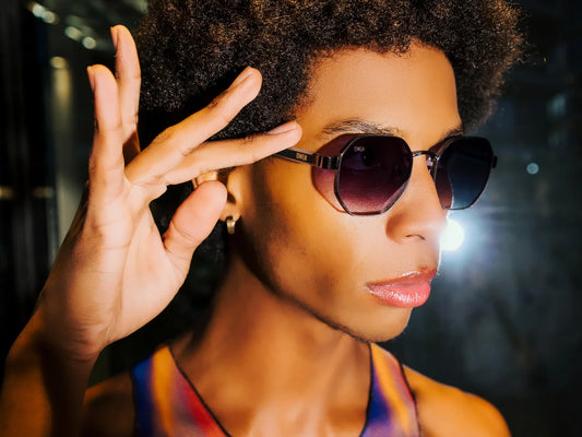 Mujer con gafas de sol OWEИ de montura oscura, sujetando una patilla.
